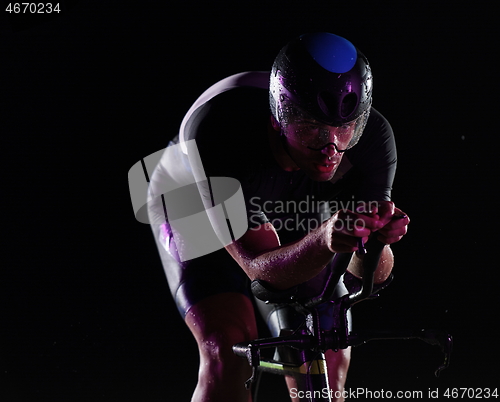 Image of triathlon athlete riding bike fast at night