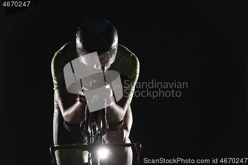 Image of triathlon athlete riding bike fast at night