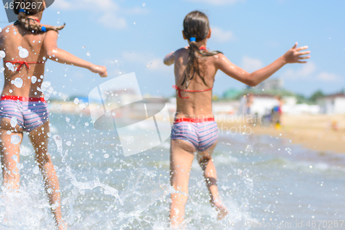 Image of Spray soars after children run along the seashore