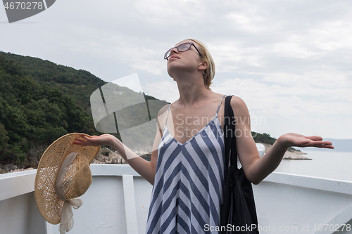 Image of Disappointed female tourist on summer cruss ship vacation, standing on rain and looking angry at overcast cloudy sky. Allways take the weather with you on summer vacations