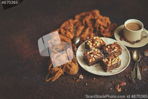 Image of The square pieces of delicious caramel cake with peanuts and brazil nuts served with milk coffee