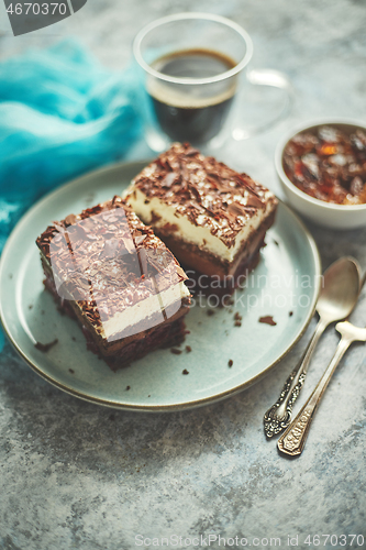 Image of Delicious chocolate cake with layers served on ceramic blue plate. With cup of fresh black coffe