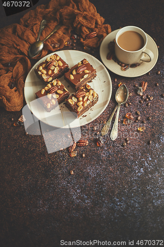 Image of The square pieces of delicious caramel cake with peanuts and brazil nuts served with milk coffee