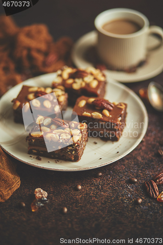 Image of Chocolate cake with caramel frosting, pecans and hot coffee, on rustic background. Freshly baked