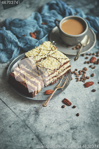 Image of Homemade layered cake sprinkled with white chocolate. Served with cup of coffee on a gray concrete