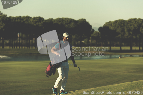 Image of golfer  walking and carrying bag