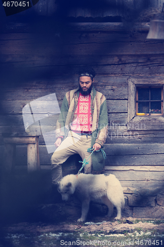 Image of hipster with dog in front of wooden house