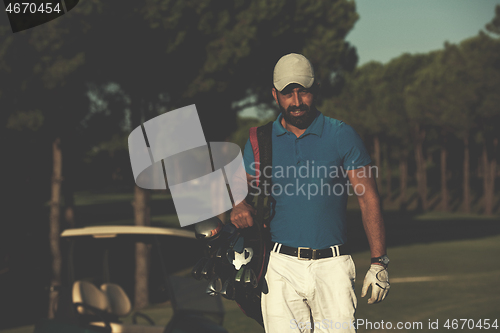 Image of golfer  walking and carrying golf  bag