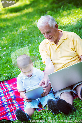 Image of grandfather and child in park using tablet