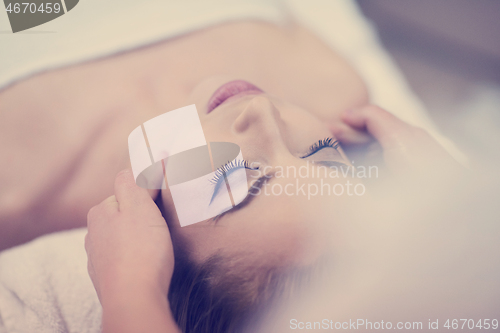 Image of woman getting face and head  massage in spa salon