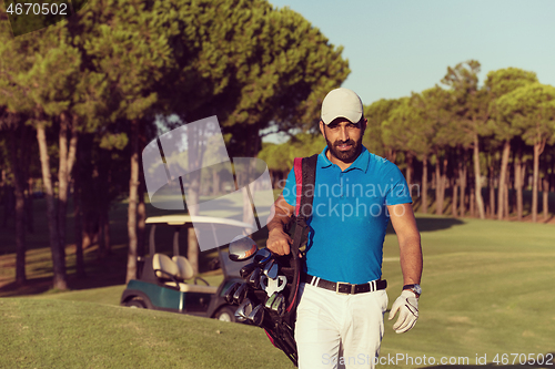 Image of golfer  walking and carrying golf  bag