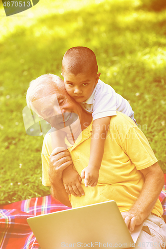 Image of grandfather and child using laptop