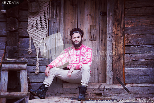 Image of portrait of young hipster in front of wooden house