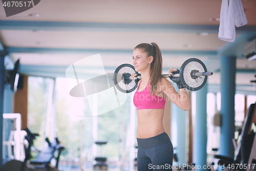 Image of young woman in fitness gym lifting  weights