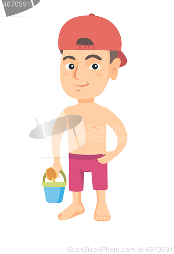 Image of Caucasian boy in shorts holding pail and shovel.