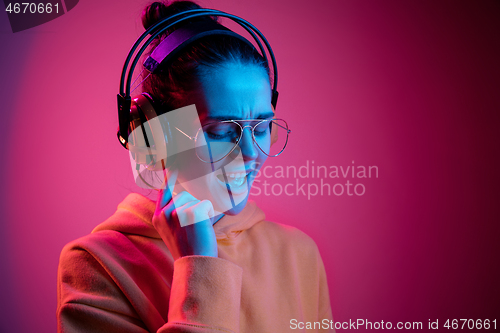 Image of Fashion pretty woman with headphones listening to music over neon background