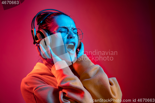 Image of Fashion pretty woman with headphones listening to music over neon background