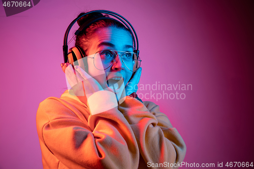 Image of Fashion pretty woman with headphones listening to music over neon background