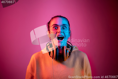 Image of Fashion pretty woman with headphones listening to music over neon background