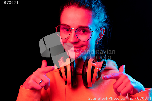 Image of Fashion pretty woman with headphones listening to music over neon background