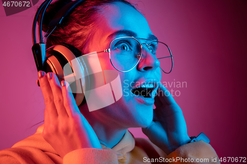 Image of Fashion pretty woman with headphones listening to music over neon background