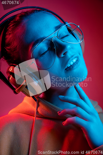 Image of Fashion pretty woman with headphones listening to music over neon background