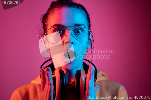 Image of Fashion pretty woman with headphones listening to music over neon background