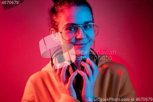 Image of Fashion pretty woman with headphones listening to music over neon background