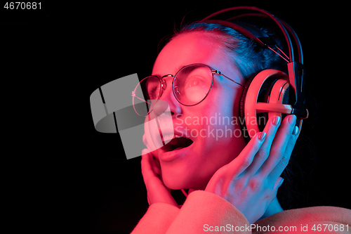 Image of Fashion pretty woman with headphones listening to music over neon background