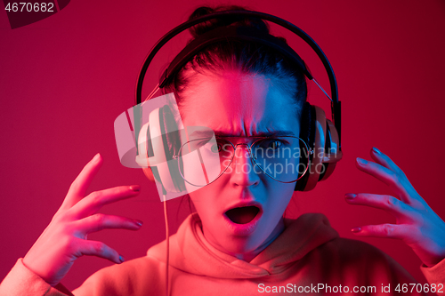 Image of Fashion pretty woman with headphones listening to music over neon background