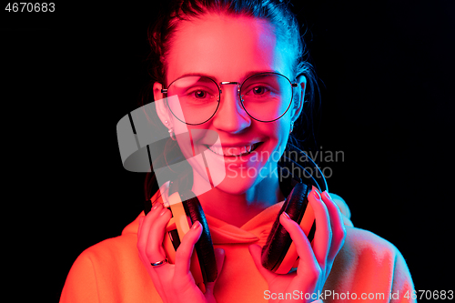 Image of Fashion pretty woman with headphones listening to music over neon background