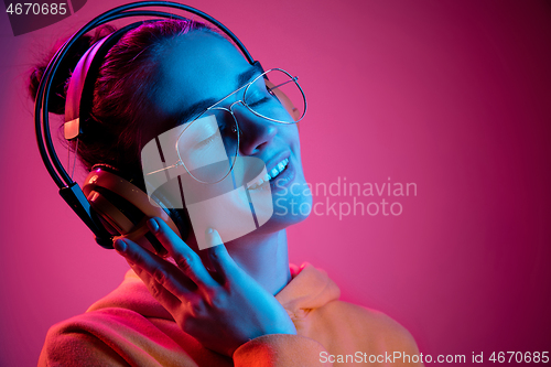 Image of Fashion pretty woman with headphones listening to music over neon background
