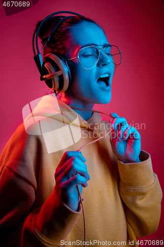 Image of Fashion pretty woman with headphones listening to music over neon background