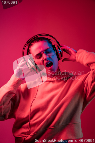 Image of Fashion pretty woman with headphones listening to music over neon background