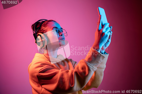 Image of Fashion pretty woman with headphones listening to music over neon background