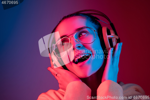 Image of Fashion pretty woman with headphones listening to music over neon background