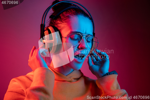 Image of Fashion pretty woman with headphones listening to music over neon background