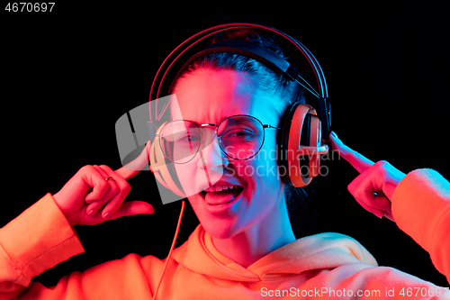 Image of Fashion pretty woman with headphones listening to music over neon background