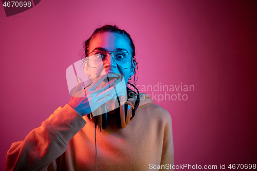 Image of Fashion pretty woman with headphones listening to music over neon background