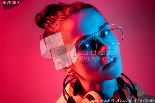 Image of Fashion pretty woman with headphones listening to music over neon background