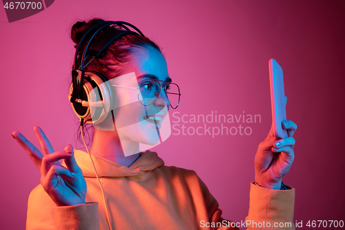 Image of Fashion pretty woman with headphones listening to music over neon background