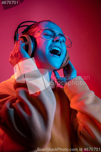 Image of Fashion pretty woman with headphones listening to music over neon background