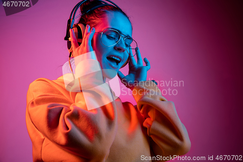 Image of Fashion pretty woman with headphones listening to music over neon background