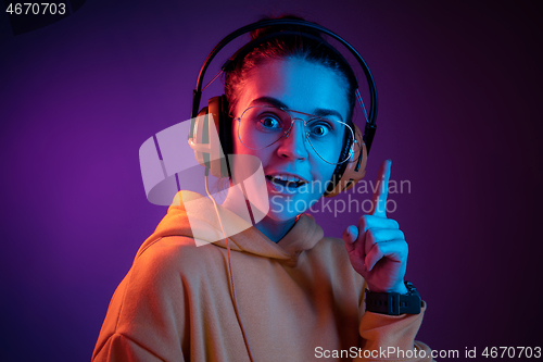 Image of Fashion pretty woman with headphones listening to music over neon background