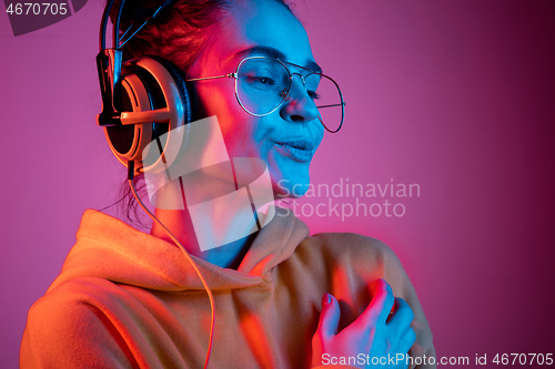 Image of Fashion pretty woman with headphones listening to music over neon background