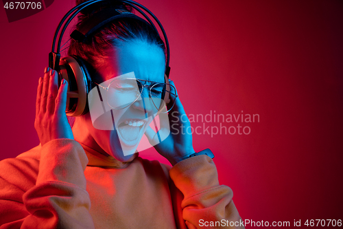 Image of Fashion pretty woman with headphones listening to music over neon background