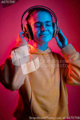 Image of Fashion pretty woman with headphones listening to music over neon background