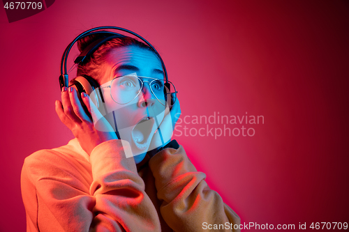 Image of Fashion pretty woman with headphones listening to music over neon background