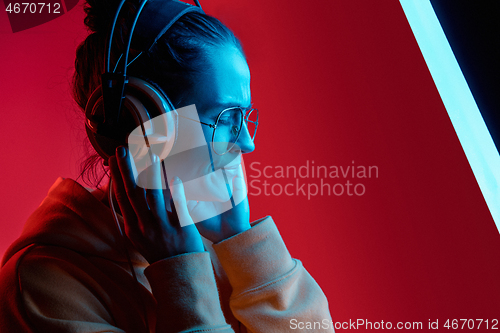 Image of Fashion pretty woman with headphones listening to music over neon background