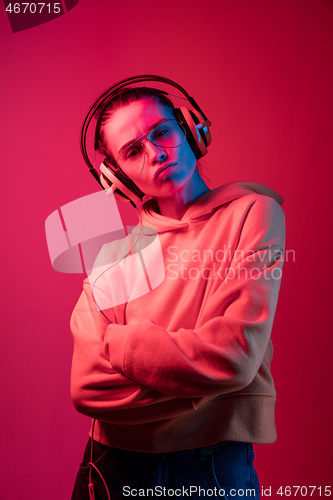 Image of Fashion pretty woman with headphones listening to music over neon background